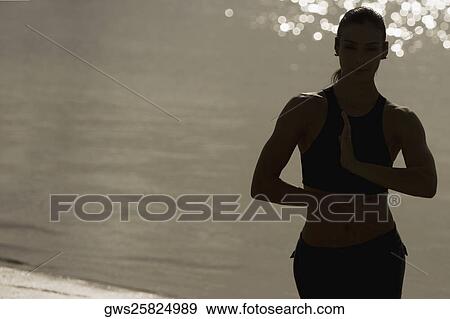 Stock Photo - Mid adult woman exercising on the beach. Fotosearch