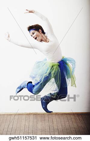 Mid adult woman jumping with her arms outstretched View Large Photo Image Stock Image - Mid adult woman jumping with her arms outstretched. Fotosearch