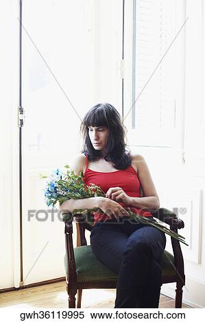Mid adult woman sitting in an armchair and holding a bunch of flowers View Large Photo Image Stock Photography - Mid adult woman sitting in an armchair and holding a bunch of flowers. Fotosearch