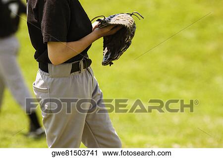 Stock Image - Mid section view of a baseball player holding a baseball glove. Fotosearch