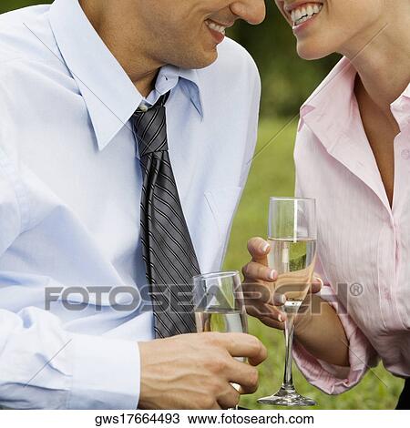 Stock Image - Mid section view of a mid adult man and a young woman holding champagne flutes. Fotosearch