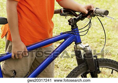 Mid section view of a teenage boy holding a bicycle View Large Photo Image Stock Image - Mid section view of a teenage boy holding a bicycle. Fotosearch