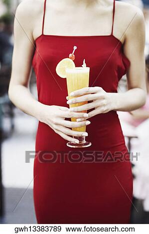 Stock Photo - Mid section view of a woman holding a glass of juice . Fotosearch