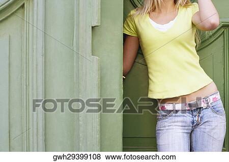 Stock Photo - Mid section view of a woman leaning against a wall . Fotosearch