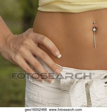 Mid section view of a woman with her hand on her hip and showing her pierced belly button View Large Photo Image Stock Photograph - Mid section view of a woman with her hand on her hip and showing her pierced belly button. Fotosearch