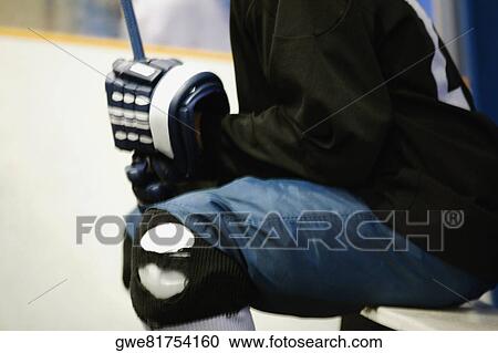 Stock Image - Mid section view of an ice hockey player holding an ice hockey stick. Fotosearch