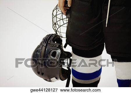 Stock Photo - Mid section view of an ice hockey player holding a helmet. Fotosearch