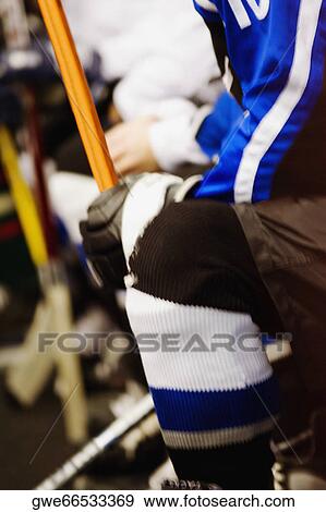 Stock Photo - Mid section view of an ice hockey player holding an ice hockey stick. Fotosearch
