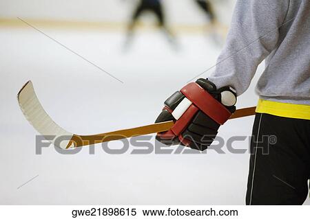 Stock Photography - Mid section view of an ice hockey player holding an ice hockey stick. Fotosearch