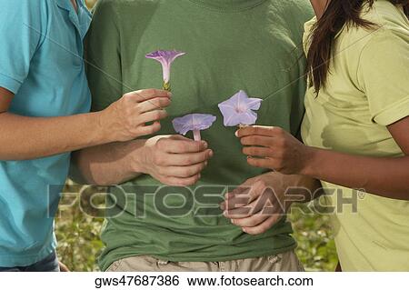 Mid section view of three friends holding flowers View Large Photo Image Stock Photograph - Mid section view of three friends holding flowers. Fotosearch