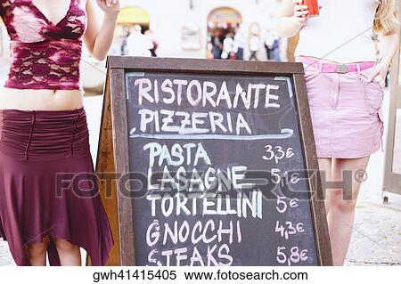 Stock Photography - Mid section view of two women standing near a signboard . Fotosearch