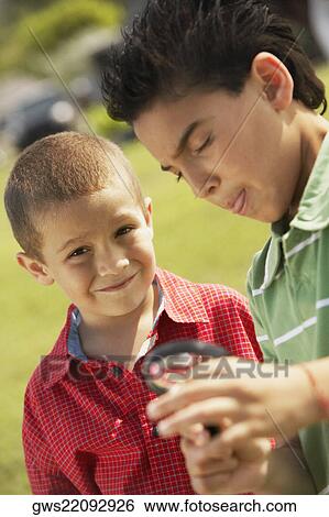 Portrait of a boy and his friend holding a magnifying glass View Large Photo Image Stock Photograph - Portrait of a boy and his friend holding a magnifying glass. Fotosearch