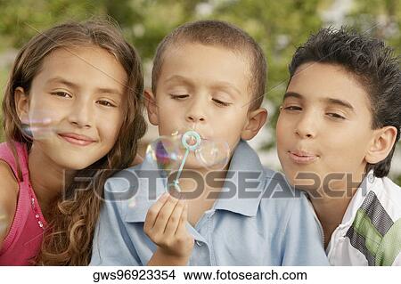 Picture - Portrait of a boy blowing bubbles with his sister and brother . Fotosearch