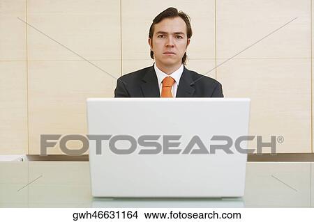 Picture - Portrait of a businessman in front of a laptop. Fotosearch