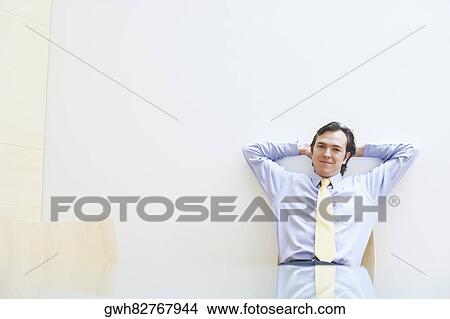 Portrait of a businessman relaxing with his hands behind his head in an office View Large Photo Image Picture - Portrait of a businessman relaxing with his hands behind his head in an office. Fotosearch