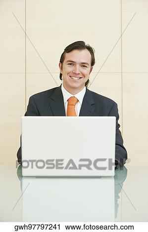 Stock Image - Portrait of a businessman sitting in front of a laptop. Fotosearch
