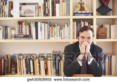 Portrait of a businessman sitting in front of book shelves View Large Photo Image Stock Photography - Portrait of a businessman sitting in front of book shelves. Fotosearch