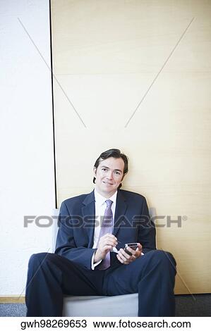 Stock Image - Portrait of a businessman using a personal data assistant. Fotosearch