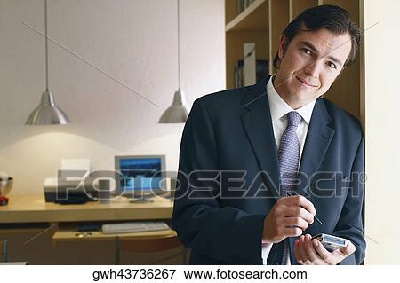 Stock Photo - Portrait of a businessman using a personal data assistant. Fotosearch