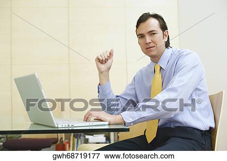 Stock Photo - Portrait of a businessman using a laptop in an office. Fotosearch
