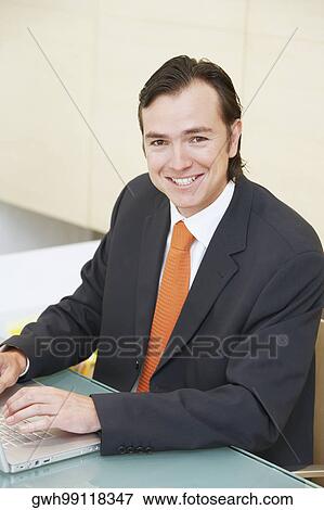 Portrait of a businessman using a laptop and smiling View Large Photo Image Stock Photo - Portrait of a businessman using a laptop and smiling. Fotosearch