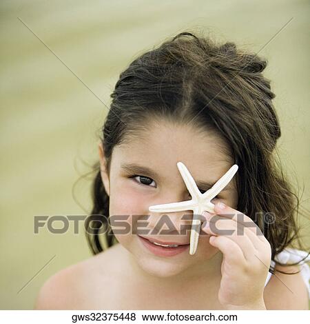 Portrait of a girl holding a star fish in front of her eye View Large Photo Image Stock Photo - Portrait of a girl holding a star fish in front of her eye. Fotosearch