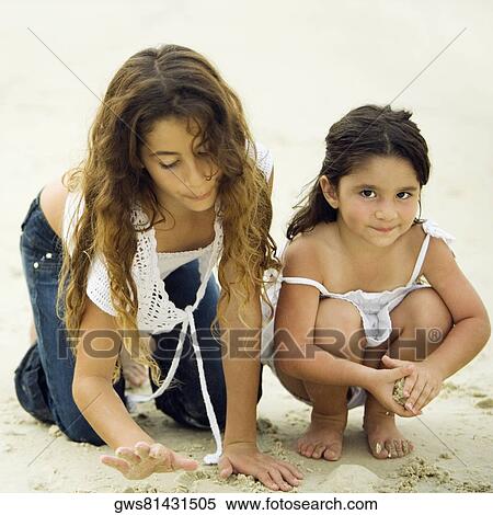 Stock Photography - Portrait of a girl playing with her sister on the beach. Fotosearch