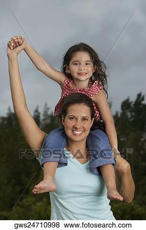 Stock Photo - Portrait of a girl sitting on her mother's shoulders and smiling. Fotosearch