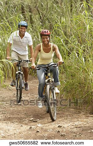 Stock Image - Portrait of a mid adult man and a young woman riding bicycles. Fotosearch