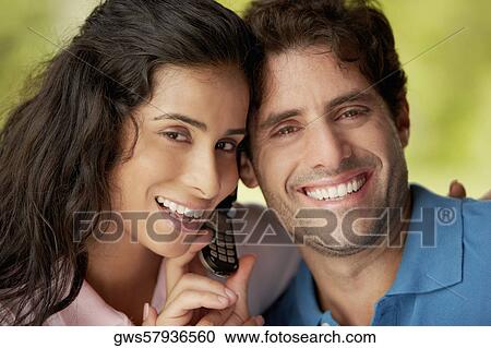 Portrait of a mid adult man and a young woman holding a mobile phone View Large Photo Image Stock Image - Portrait of a mid adult man and a young woman holding a mobile phone. Fotosearch