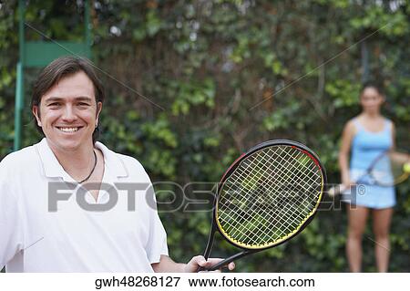 Portrait of a mid adult man and a young woman holding tennis rackets on a tennis court View Large Photo Image Stock Photo - Portrait of a mid adult man and a young woman holding tennis rackets on a tennis court. Fotosearch