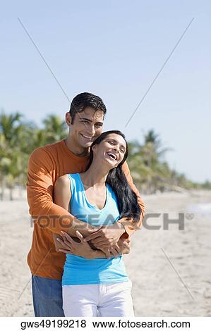 Stock Photo - Portrait of a mid adult man embracing a young woman from behind. Fotosearch