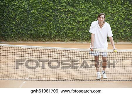 Portrait of a mid adult man holding a tennis ball and a tennis racket View Large Photo Image Stock Photograph - Portrait of a mid adult man holding a tennis ball and a tennis racket. Fotosearch