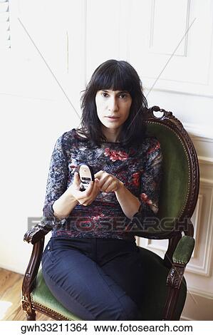 Picture - Portrait of a mid adult woman holding a mobile phone. Fotosearch