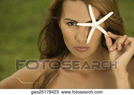 Portrait of a mid adult woman holding a star fish in front of her eye View Large Photo Image Stock Image - Portrait of a mid adult woman holding a star fish in front of her eye. Fotosearch