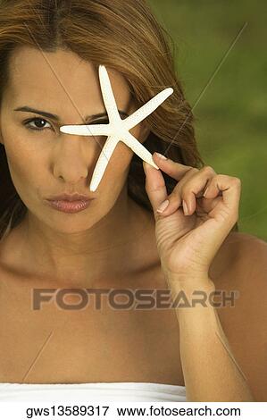 Portrait of a mid adult woman holding a star fish in front of her eye View Large Photo Image Stock Photo - Portrait of a mid adult woman holding a star fish in front of her eye. Fotosearch