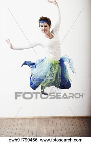 Stock Photograph - Portrait of a mid adult woman jumping. Fotosearch