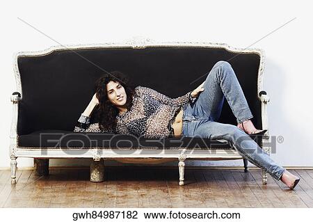 Stock Image - Portrait of a mid adult woman lying on a couch. Fotosearch