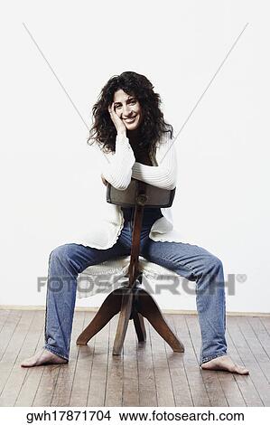 Portrait of a mid adult woman sitting on a stool and smiling View Large Photo Image Picture - Portrait of a mid adult woman sitting on a stool and smiling. Fotosearch