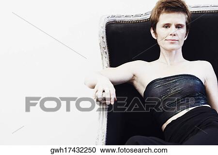 Portrait of a mid adult woman sitting on a couch View Large Photo Image Stock Image - Portrait of a mid adult woman sitting on a couch. Fotosearch