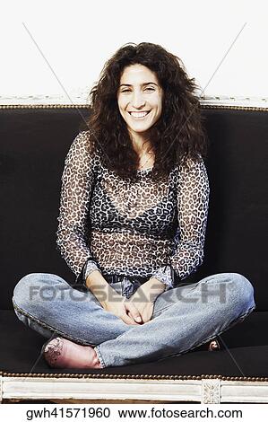 Stock Image - Portrait of a mid adult woman sitting on a couch. Fotosearch