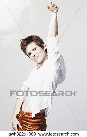 Stock Image - Portrait of a mid adult woman standing with her hand raised. Fotosearch