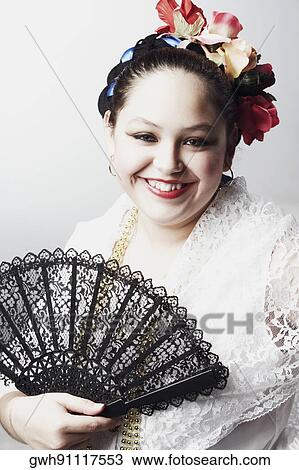 Stock Image - Portrait of a teenage girl holding a folding fan and smiling. Fotosearch
