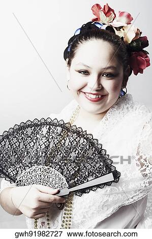 Stock Photo - Portrait of a teenage girl holding a folding fan and smiling. Fotosearch