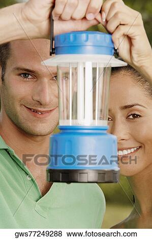Portrait of a young couple holding a lantern in front of their faces View Large Photo Image Stock Photo - Portrait of a young couple holding a lantern in front of their faces. Fotosearch