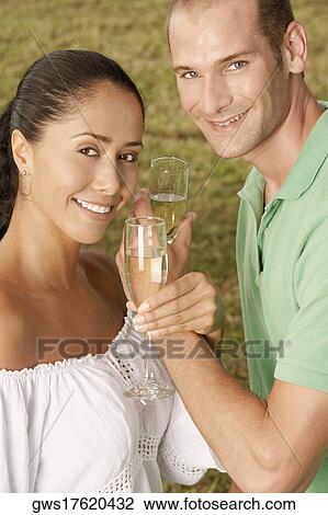 Portrait of a young couple holding champagne flutes View Large Photo Image Stock Image - Portrait of a young couple holding champagne flutes. Fotosearch