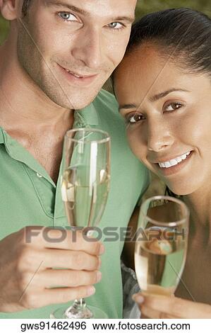 Portrait of a young couple holding champagne flutes View Large Photo Image Stock Photograph - Portrait of a young couple holding champagne flutes. Fotosearch