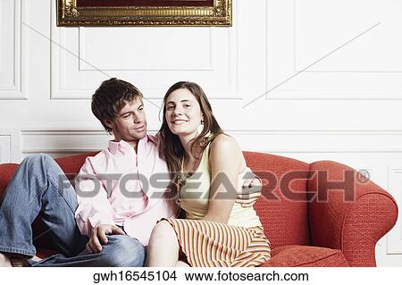 Portrait of a young couple sitting on a couch View Large Photo Image Picture - Portrait of a young couple sitting on a couch. Fotosearch