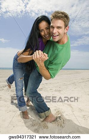 Portrait of a young couple smiling and standing on the beach View Large Photo Image Stock Image - Portrait of a young couple smiling and standing on the beach. Fotosearch