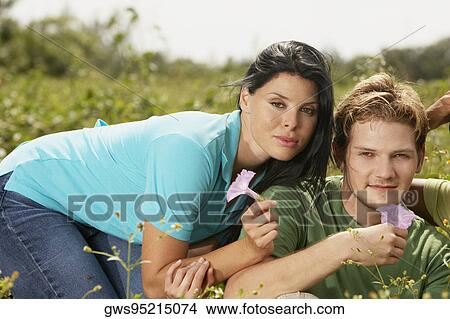 Portrait of a young man and a young woman holding flowers View Large Photo Image Picture - Portrait of a young man and a young woman holding flowers. Fotosearch